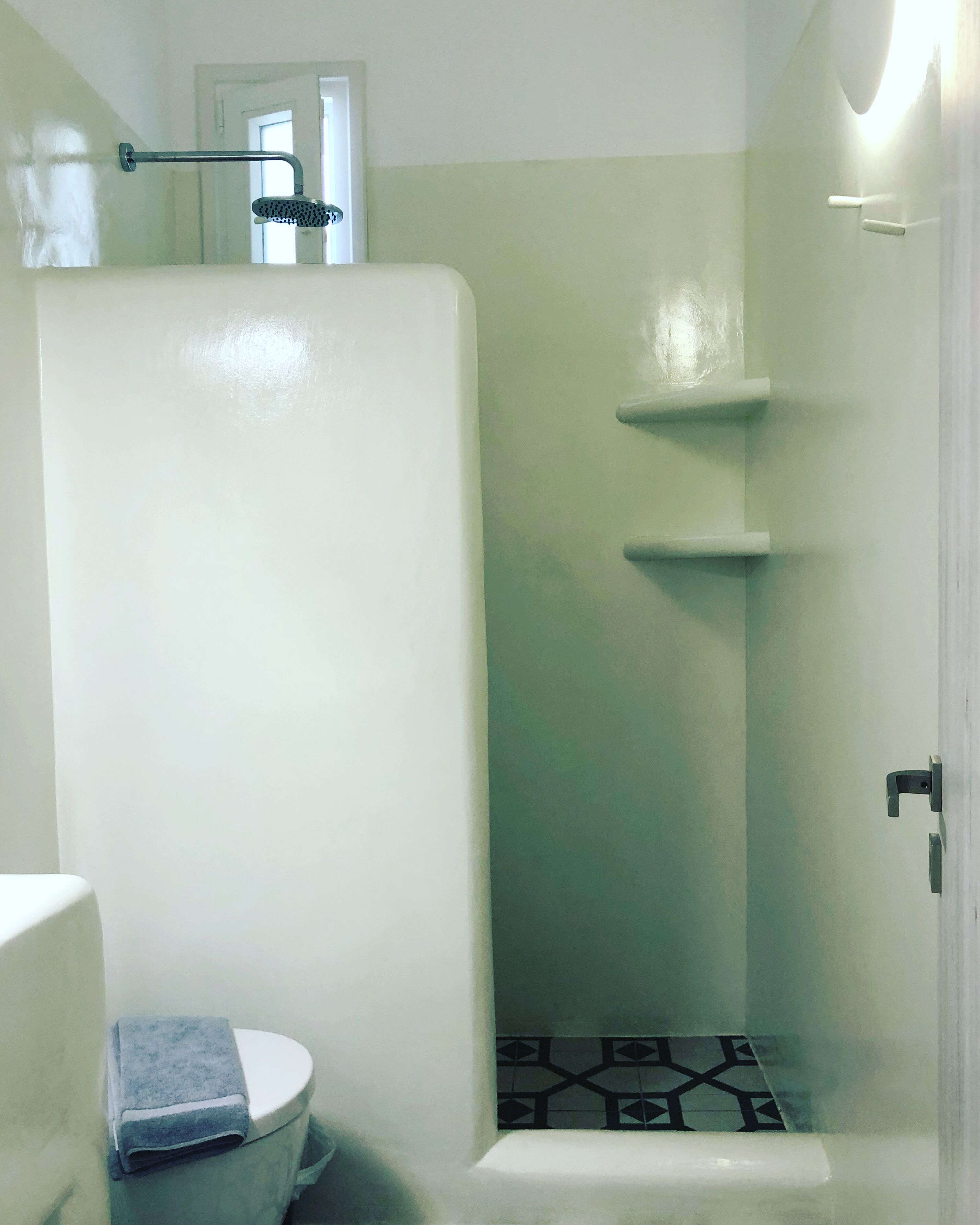 Een badkamer met een wit toilet, een douche met een glazen deur en een handdoek op de vloer.