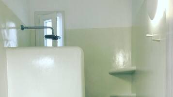 Een badkamer met een wit toilet, een douche met een glazen deur en een handdoek op de vloer.
