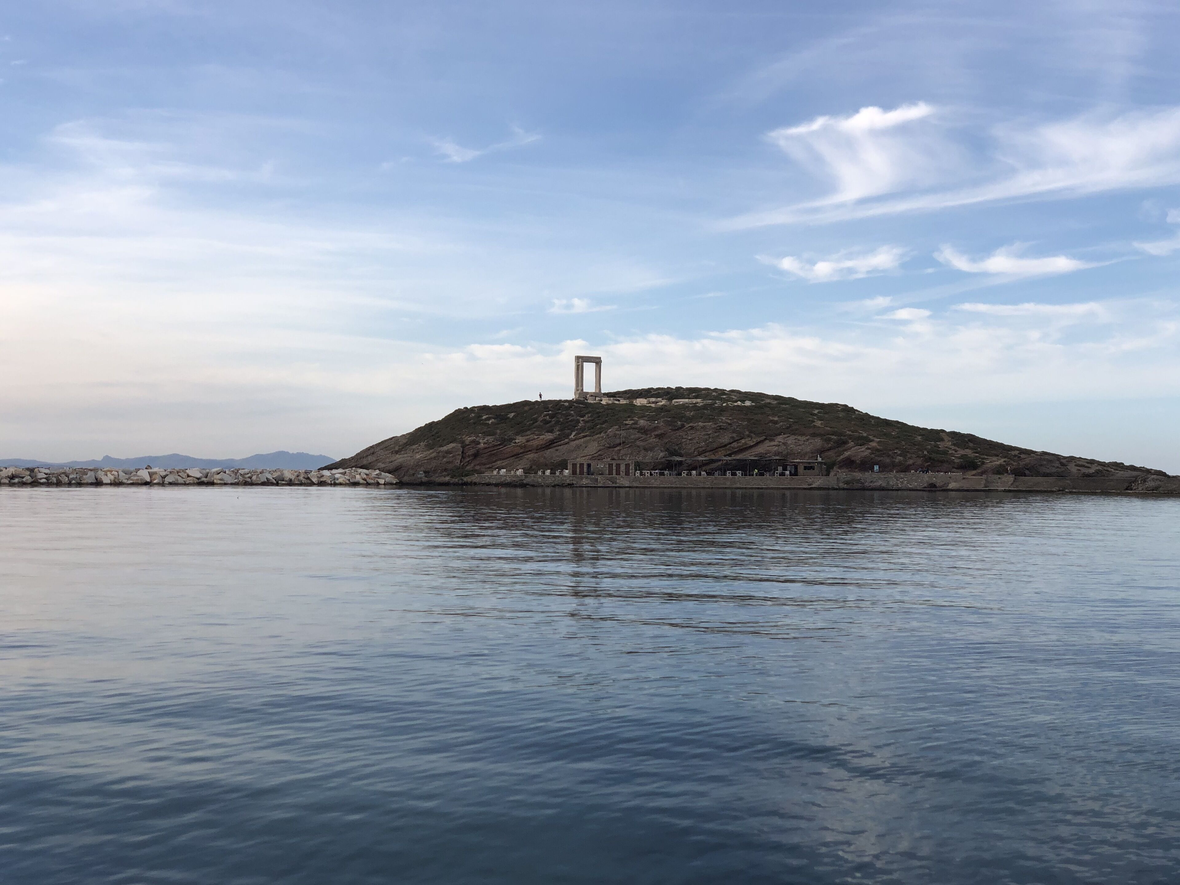 Un plan d’eau calme, avec une île rocheuse au centre, sur laquelle se dresse une haute structure.