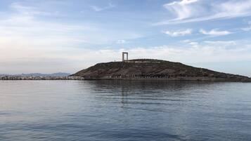 Un plan d’eau calme, avec une île rocheuse au centre, sur laquelle se dresse une haute structure.