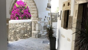 Un estrecho patio empedrado con pared de piedra y una ventana.