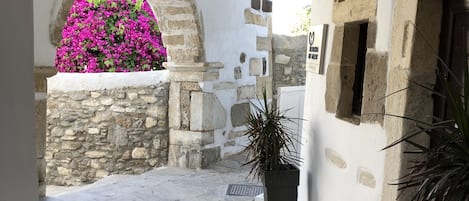 A narrow stone-paved courtyard with a stone wall and a window.