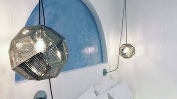 A bedroom with a bed, a blue arched wall, and two hanging lights.