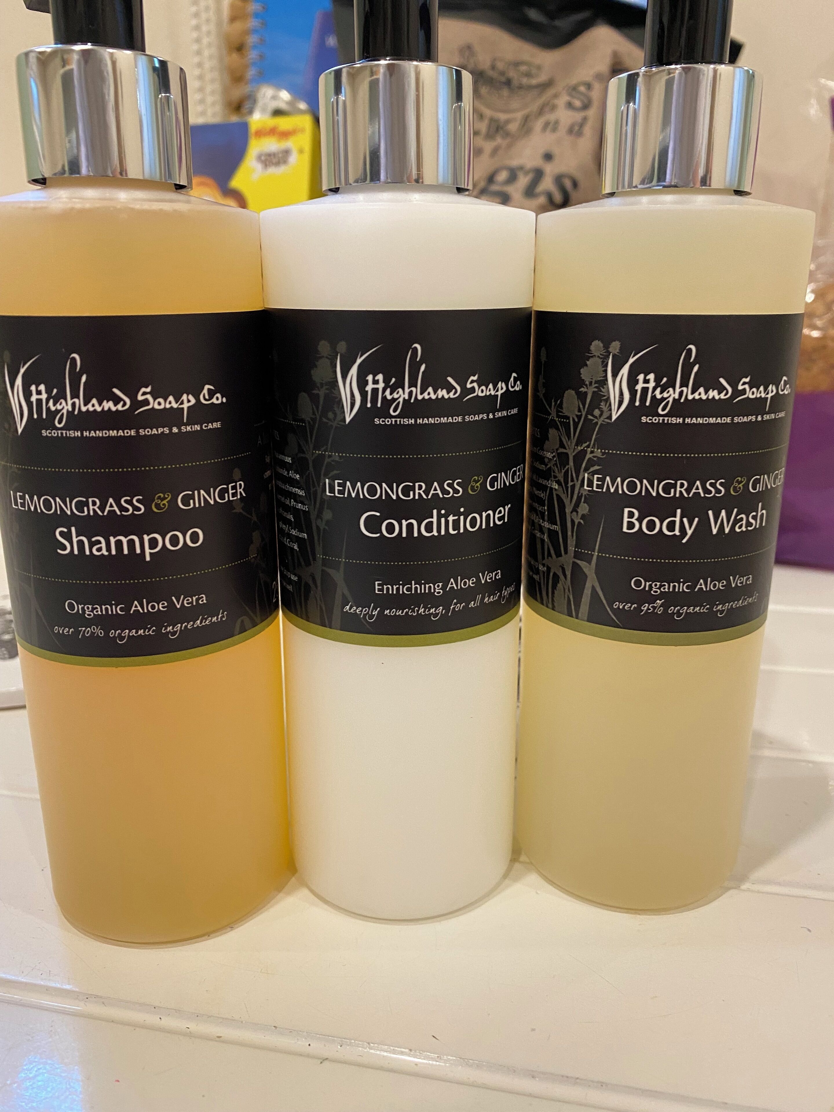 Three bottles of Highland Soap Co. products: Lemongrass & Ginger Shampoo, Conditioner, and Body Wash.