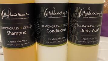 Three bottles of Highland Soap Co. products: Lemongrass & Ginger Shampoo, Conditioner, and Body Wash.