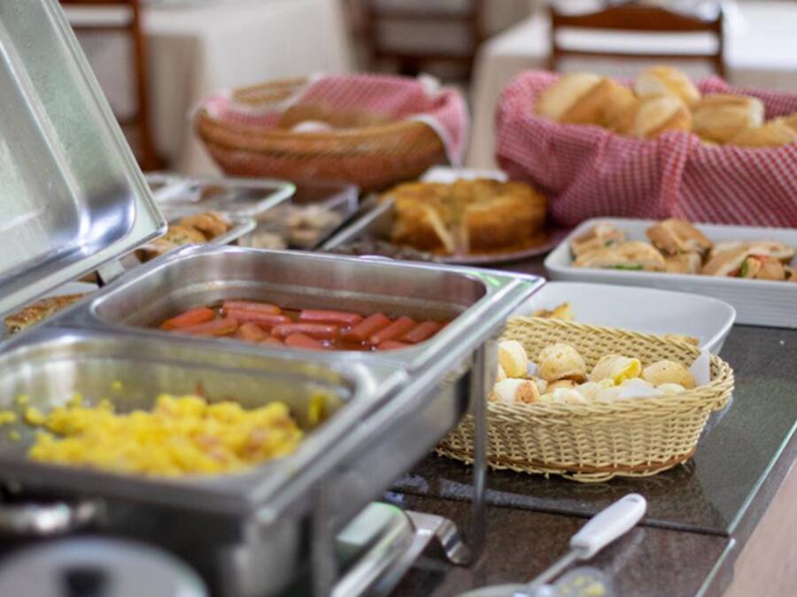 A buffet with various food items including hot dogs, scrambled eggs, and bread.