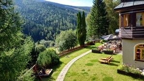 A chalet with a view of a forested valley, outdoor seating, and a barbecue area. - Alpský hotel (Spindleruv Mlyn)