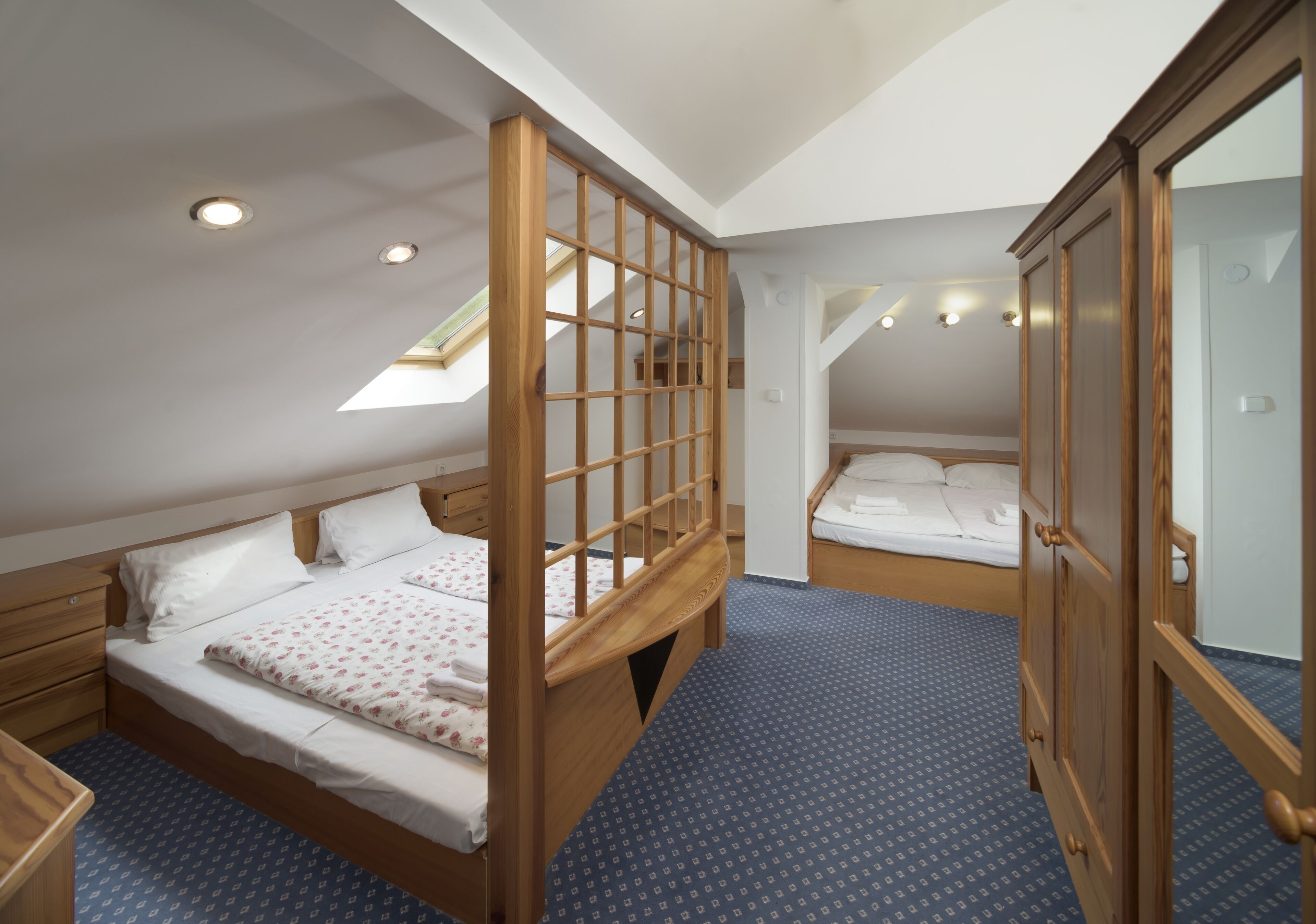 A bedroom with a bunk bed, a wooden wardrobe, and a skylight.