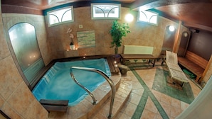 A spa area with a hot tub, wooden benches, and a potted plant. - Alpský hotel (Spindleruv Mlyn)