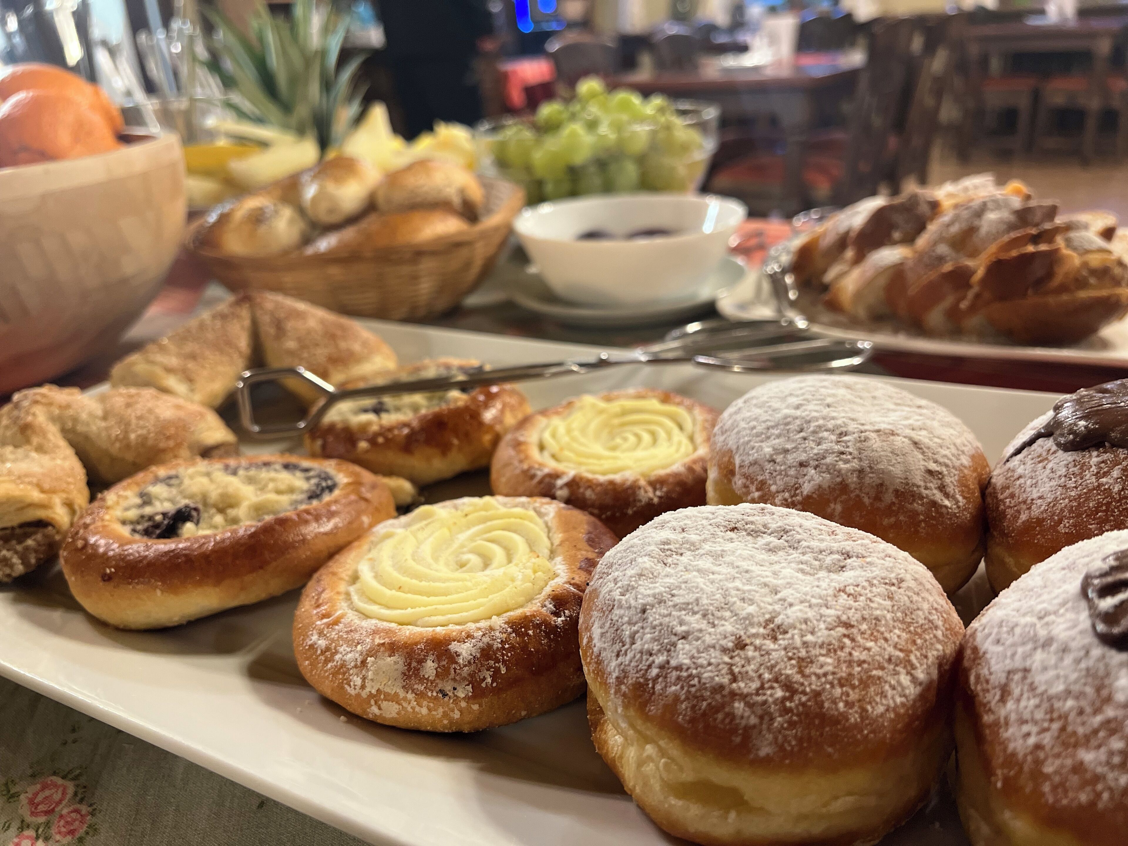 Une variété de viennoiseries présentées sur un plateau, notamment des beignets et des petits pains.