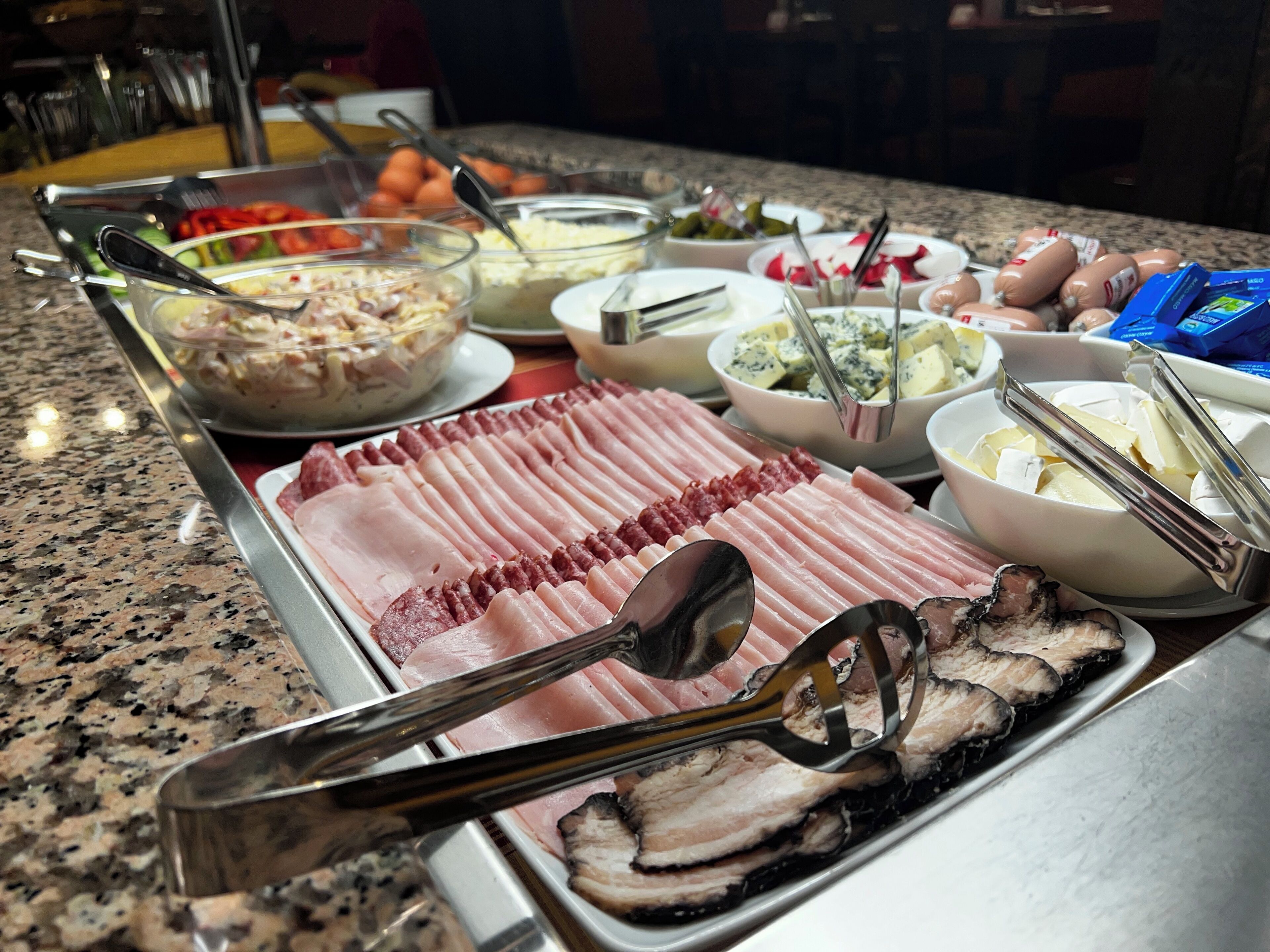 En buffet med forskellige retter, herunder kød, oste og salater.