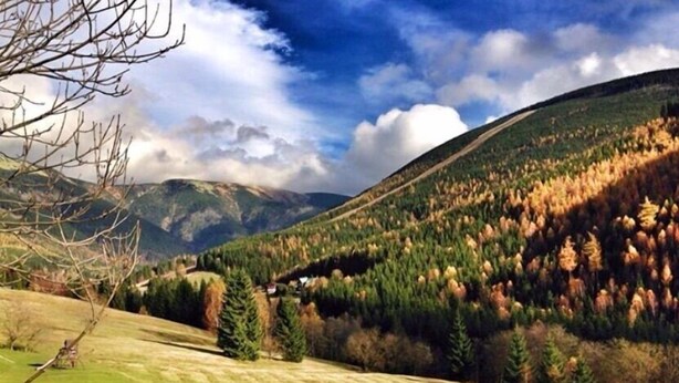 A rural landscape with a small house on a hill, surrounded by trees and open fields. - Alpský hotel (Spindleruv Mlyn)