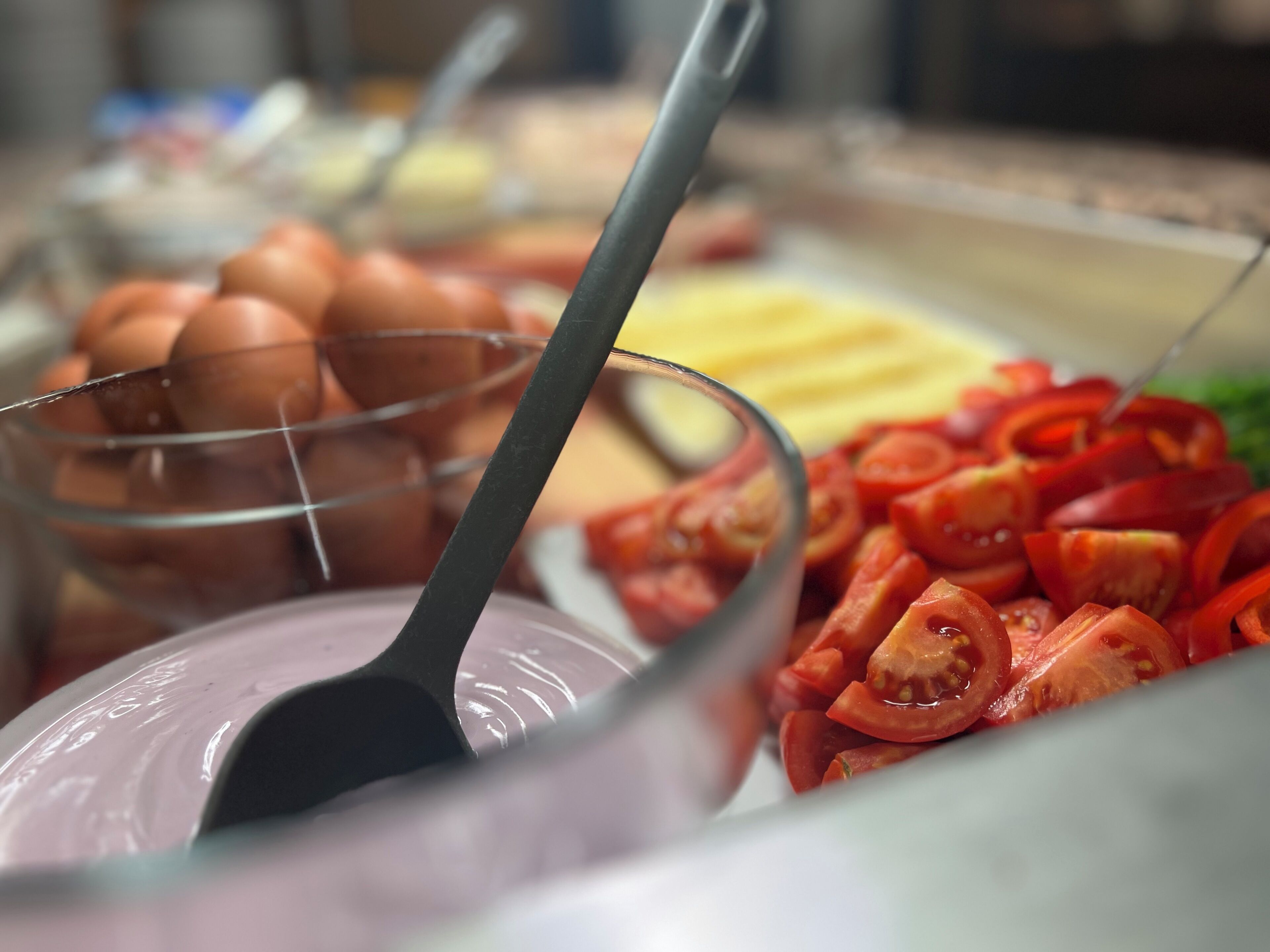 A buffet with various food items including eggs, cheese, and sliced tomatoes.