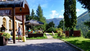 A restaurant named "Publika" with outdoor seating, surrounded by greenery and mountains. - Alpský hotel (Spindleruv Mlyn)