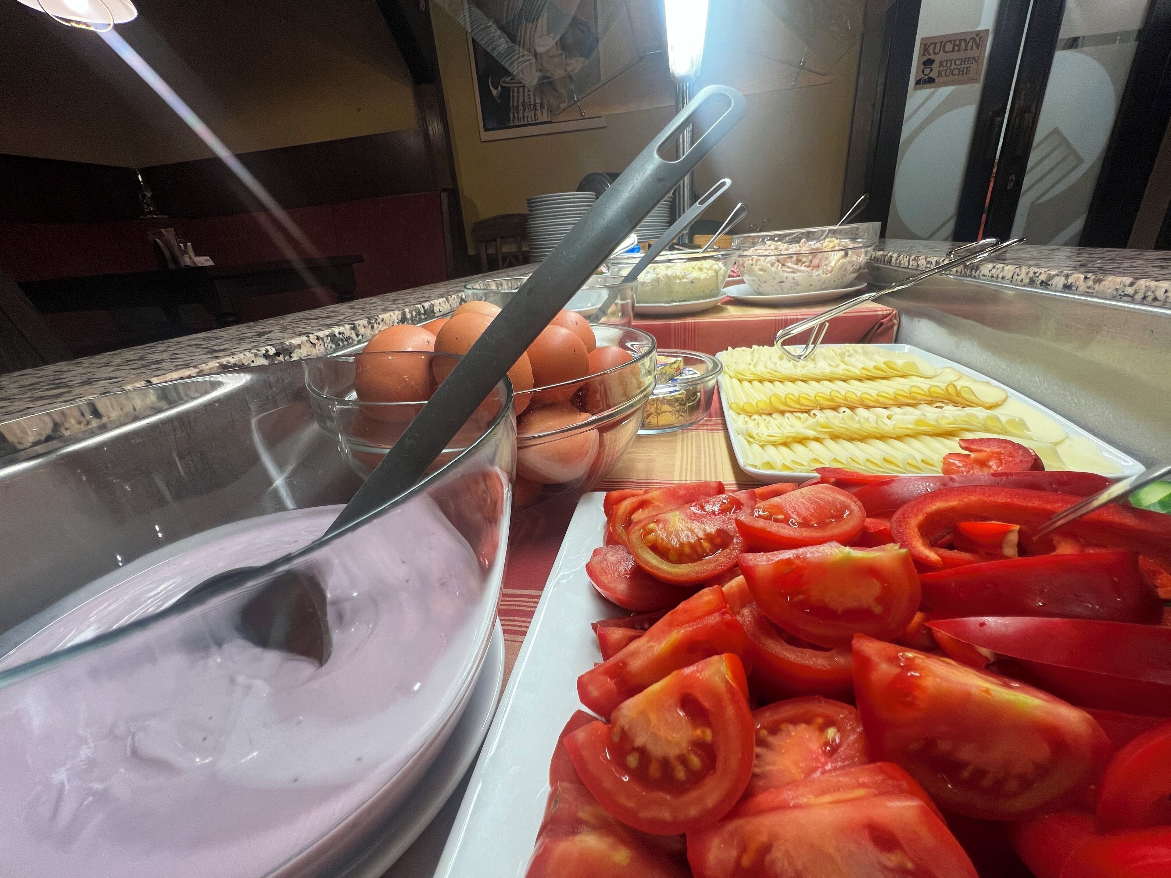 Un bufé con diversos alimentos, incluyendo tomates en rodajas, maíz y un tazón de comida morada.