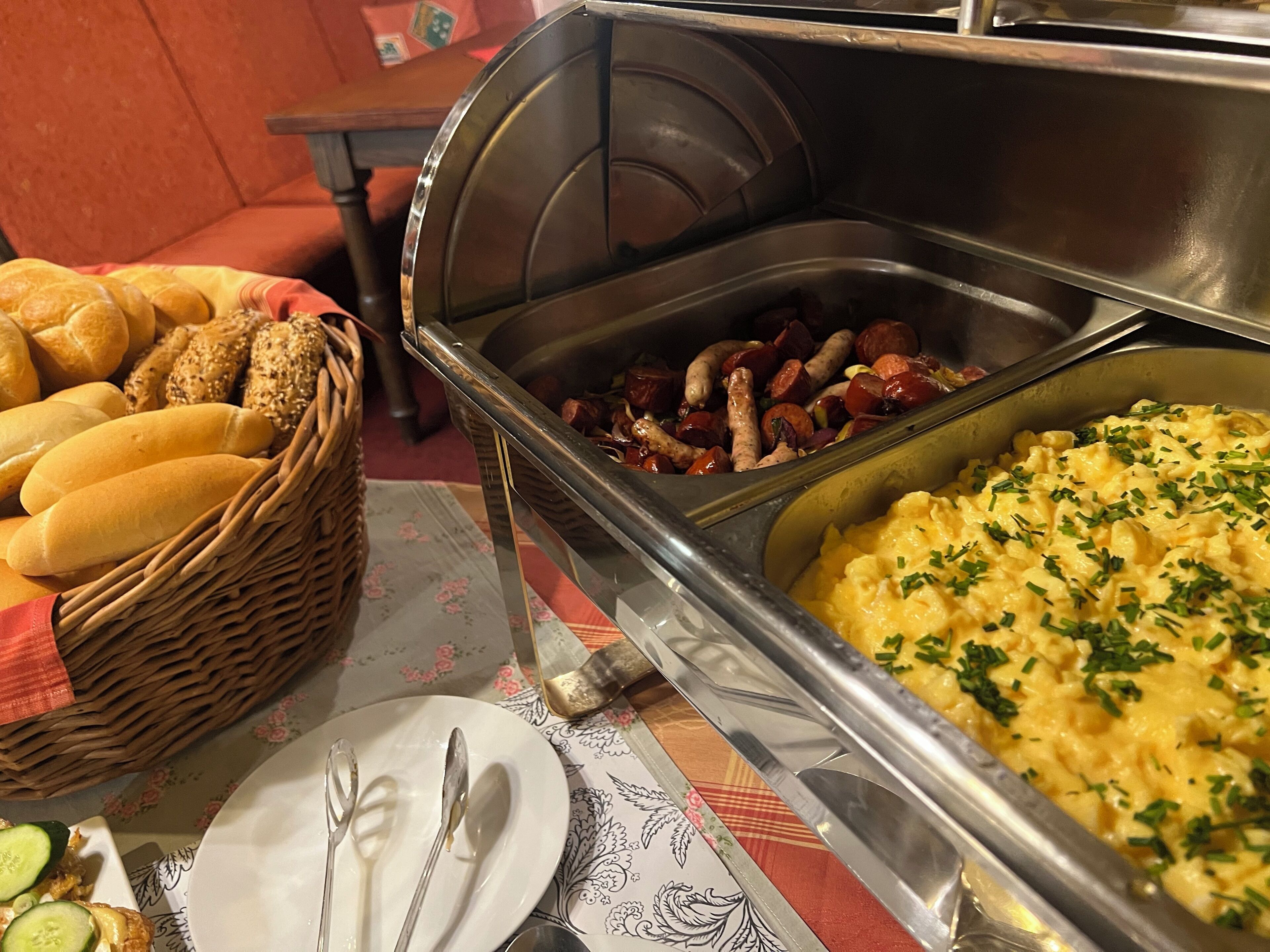 Ein Buffet mit verschiedenen Speisen, darunter Brot, Würstchen und Kartoffelpüree.