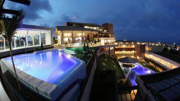 Ett semesterhotell med en stor swimmingpool, ett takförsett utomhusområde och en byggnad med flera balkonger.