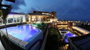A resort with a large swimming pool, a covered outdoor area, and a building with multiple balconies. - Hotel Santuário das Águias by Nobile (Aquiraz)