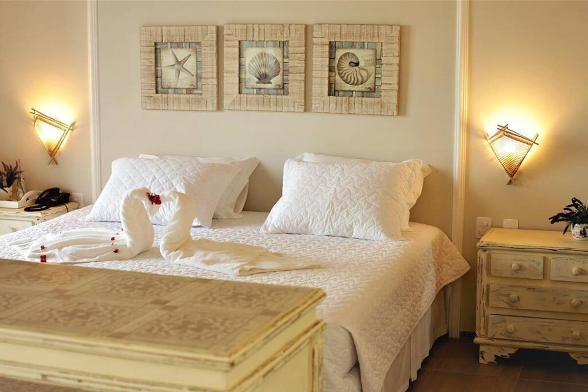 A neatly arranged hotel room with a large bed, two wall-mounted lamps, and a small bedside table.