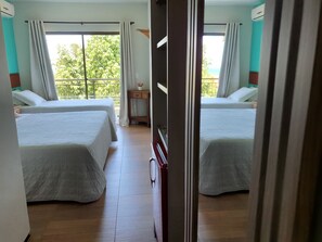 A hotel room with two beds, a small table, and a window with curtains. - Hotel Santuário das Águias by Nobile (Aquiraz)