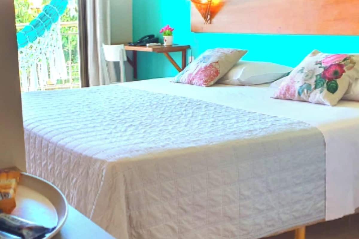 A bedroom with a bed, pillows, a bedside table, and a chair.