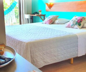 A bedroom with a bed, pillows, a bedside table, and a chair. - Hotel Santuário das Águias by Nobile (Aquiraz)