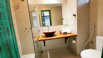 A modern bathroom with a glass shower enclosure, a wooden vanity with a bowl sink, a mirror, and a toilet.