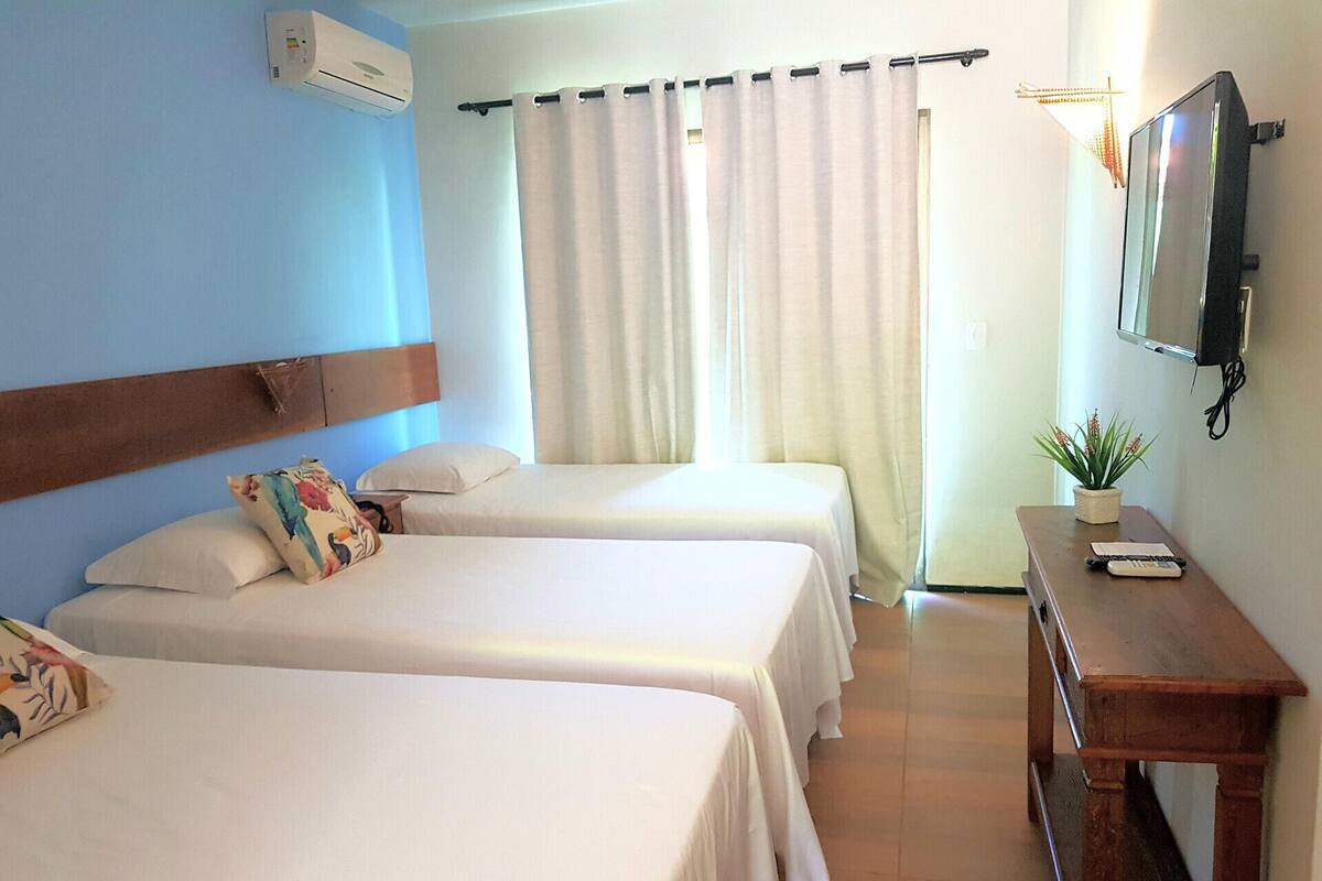 A hotel room with two beds, a wooden nightstand, a TV, and a potted plant.