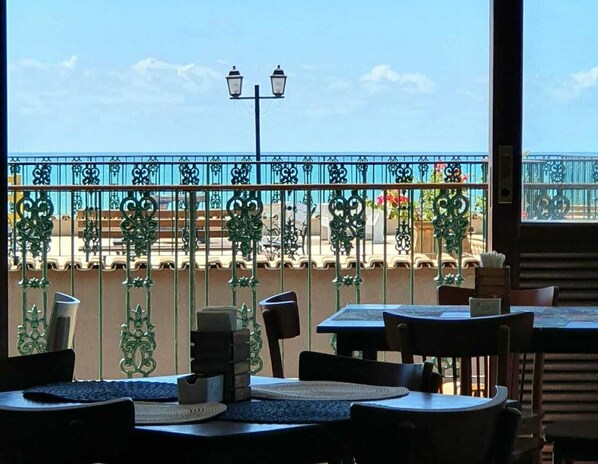 Un restaurante con terraza, vistas al mar y barandillas decorativas.
