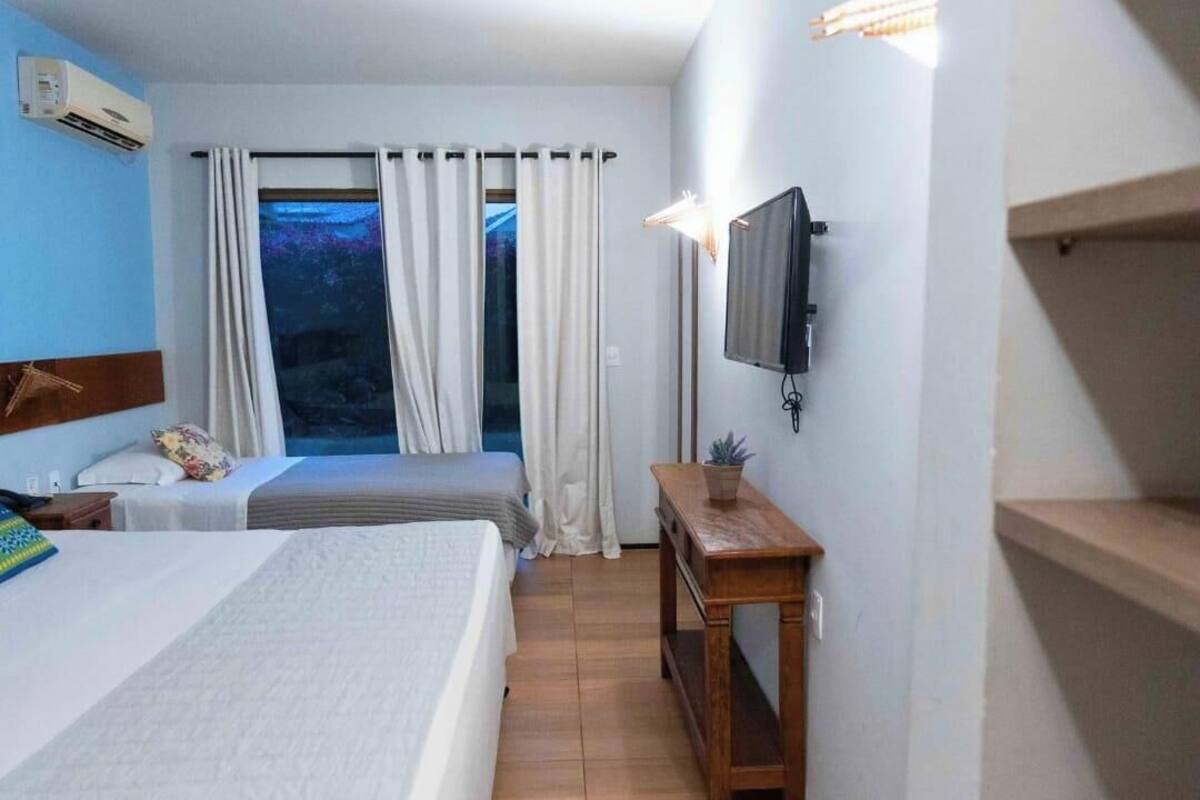 A hotel room with a bed, a TV, a small table, and a window with curtains.