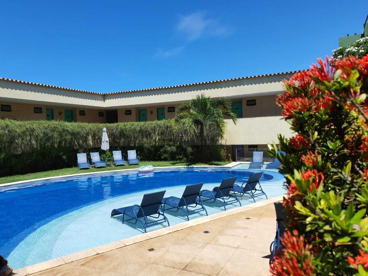 A swimming pool with lounge chairs and a building in the background.