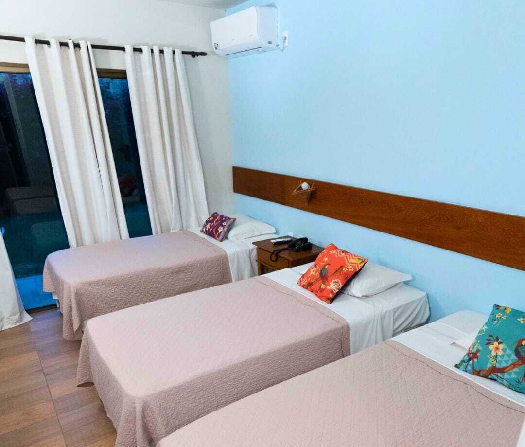 Habitación de hotel con dos camas individuales, un cabecero de madera, una mesita de noche con teléfono y un equipo de aire acondicionado.