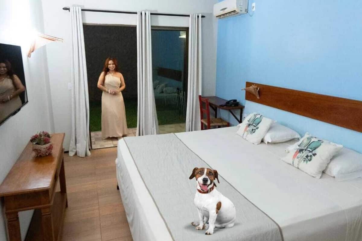 A hotel room with a bed, a desk, a chair, a TV, and a sliding glass door leading to an outdoor area.