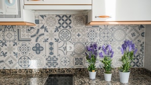 Una cocina con salpicadero decorado, encimera de granito y tres macetas.