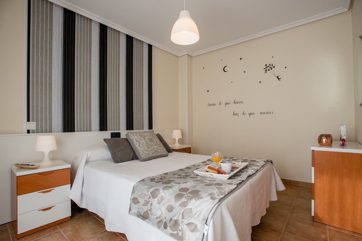 A neatly arranged bedroom with a bed, bedside tables, a dresser, and a wall with decorative stars and a crescent moon.