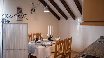 A dining area with a table set for four, wooden chairs, a candle holder, and a wall-mounted lamp.