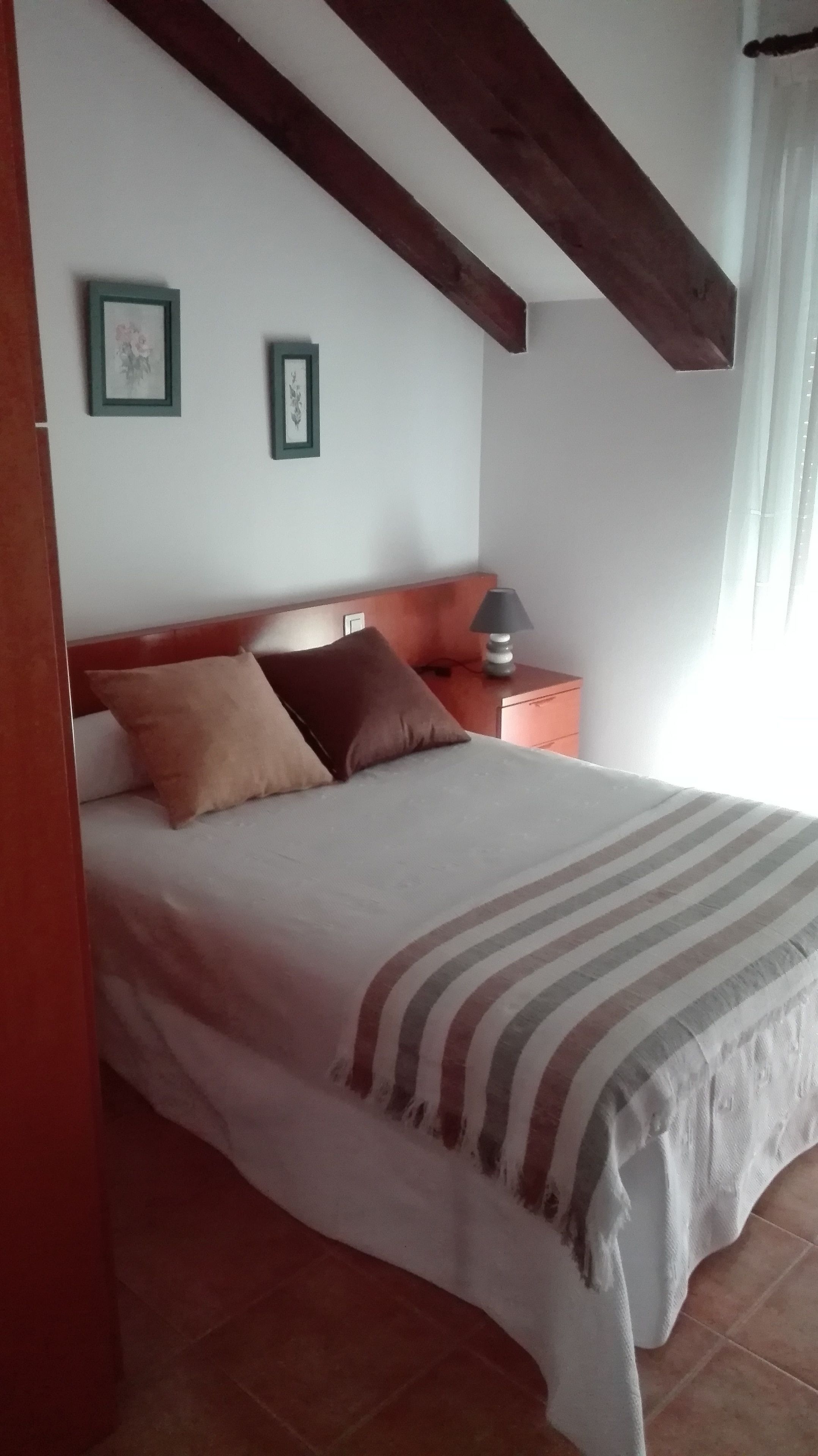 Une chambre à coucher avec un lit, des oreillers, une table de chevet et une lampe.