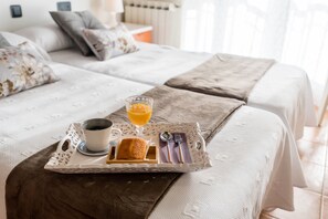 A neatly made bed with a tray of breakfast items including a cup of coffee, a glass of orange juice, and a small plate with a pastry. - Apartamentos River Santander (Santander)
