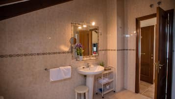 A bathroom with a sink, mirror, towel rack, and a small stool.