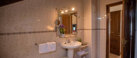 A bathroom with a sink, mirror, towel rack, and a small stool.