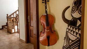 Un violín apoyado en una pared de un pasillo con una escalera y un adorno mural.