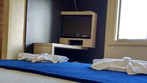 A room with a bed, a flat-screen TV, an air conditioner, and a window. - Soratur Hotel & Coworking (Criciuma)