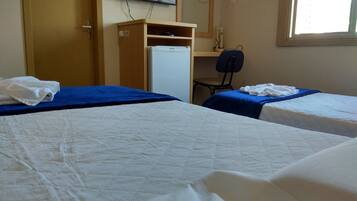 Habitación de hotel con dos camas, un escritorio, una silla, un televisor y una ventana.