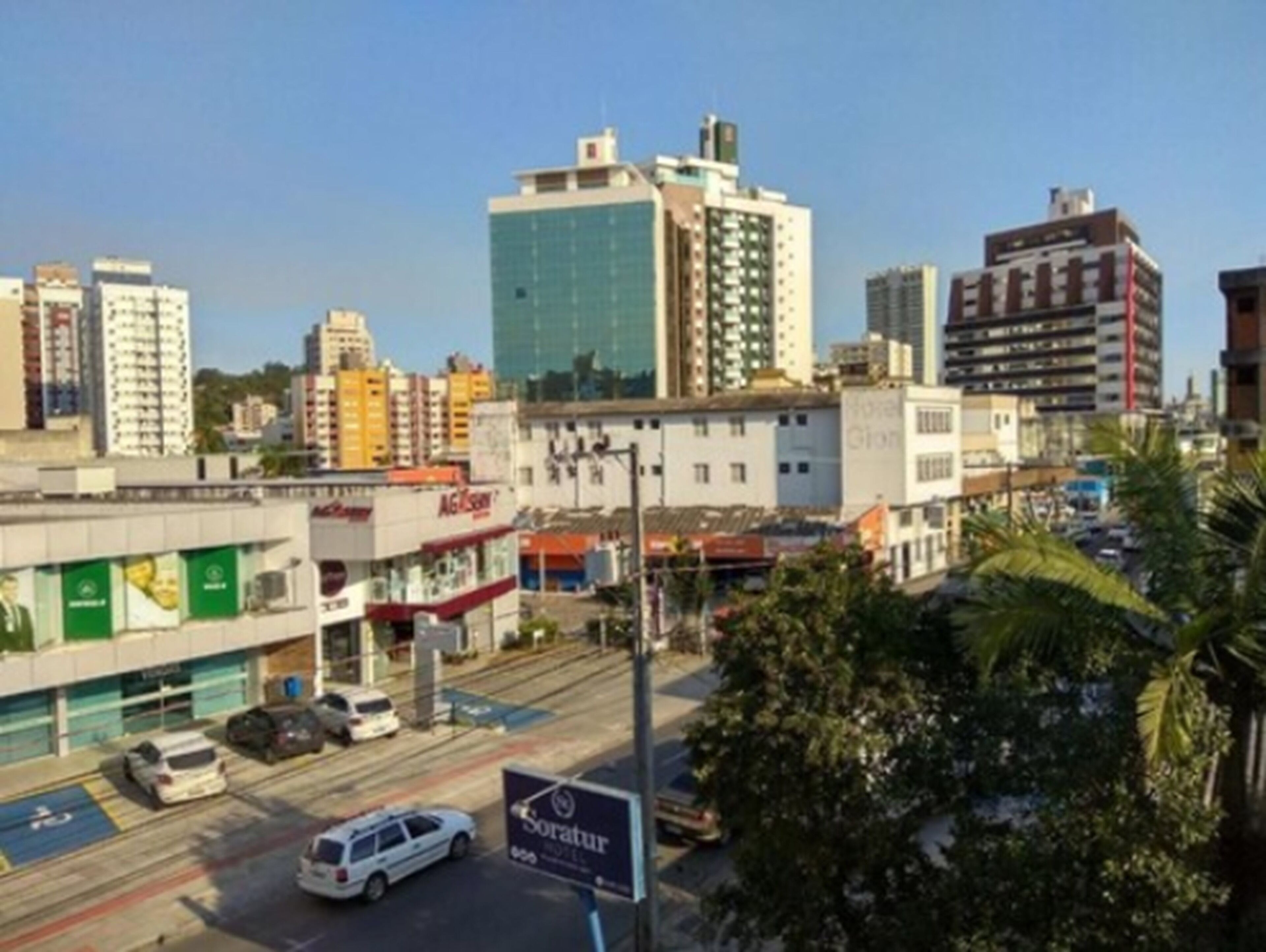 Un hotel con un letrero, una zona de estacionamiento y edificios aledaños.