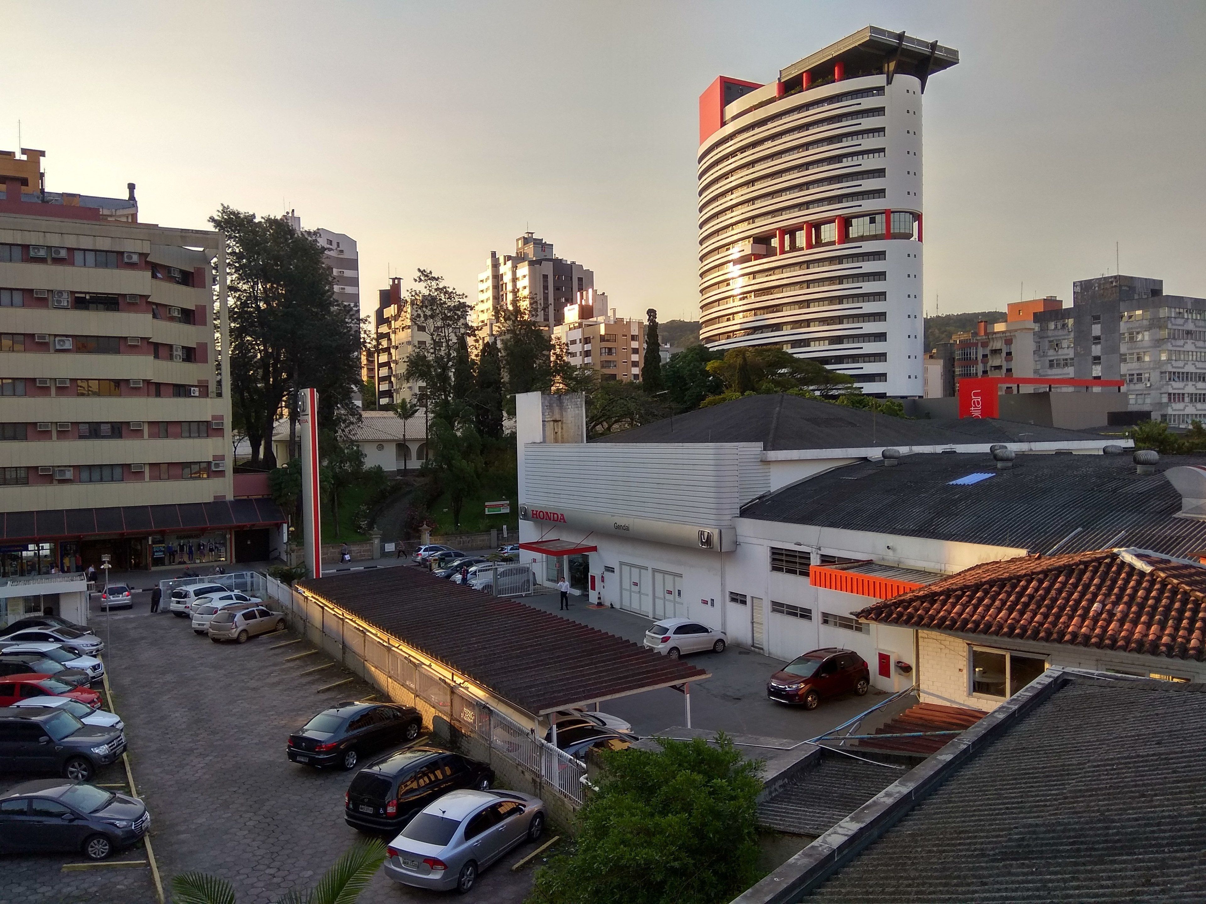 A parking lot with several cars, a Honda service station, and a building with a red and white facade.