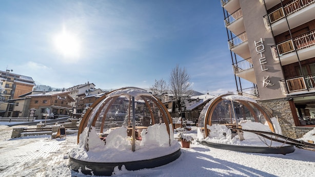 Un hotel con un patio cubierto de nieve y estructuras transparentes similares a iglús.