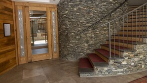 Un vestíbulo de hotel con pared de madera, pared de piedra y una escalera de caracol.