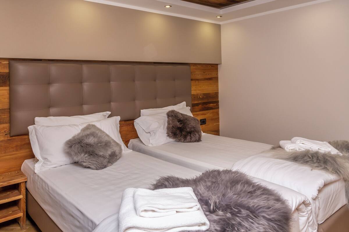 Une chambre d’hôtel avec deux lits, une tête de lit en bois, du linge de lit blanc et un oreiller moelleux.