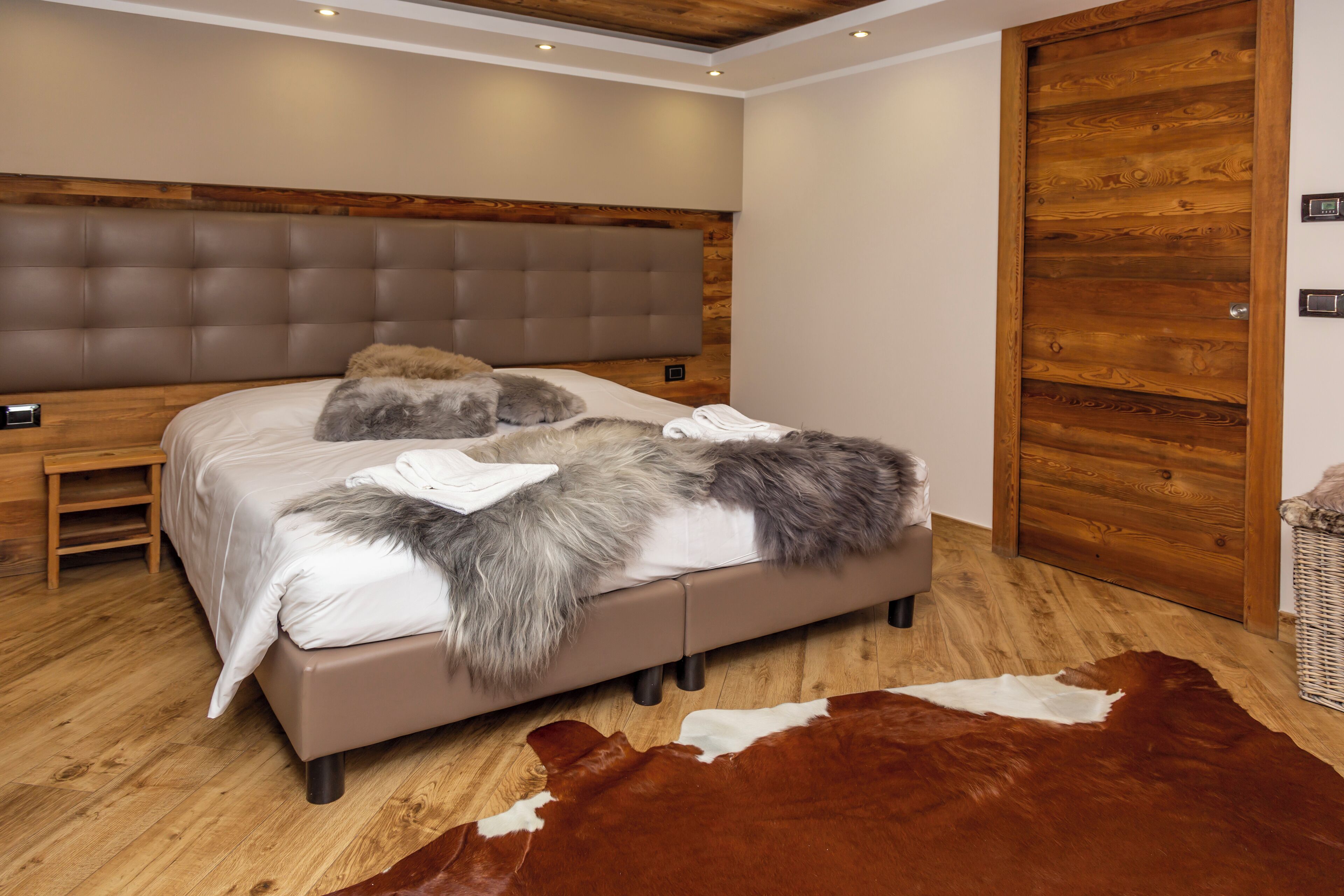 A bedroom with a large bed, wooden headboard, and a brown leather rug.