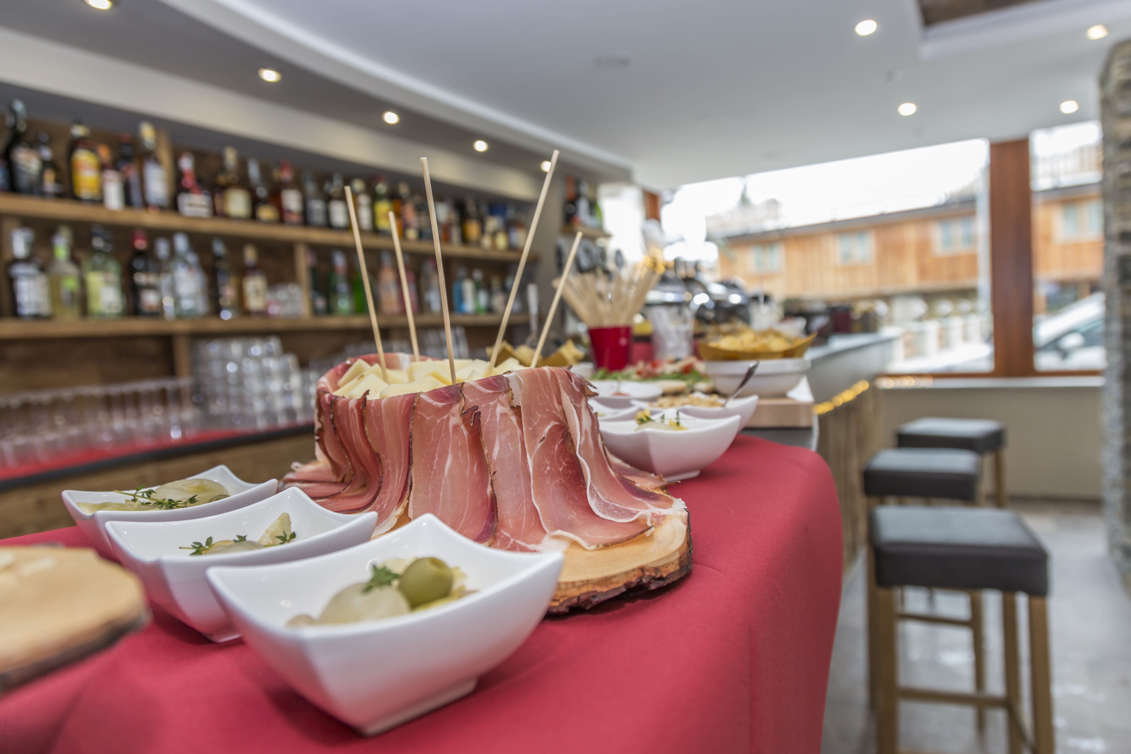 A buffet table with various dishes and a bar area with shelves of bottles in the background.